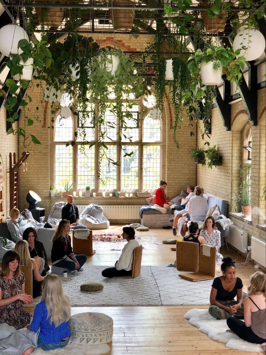 A gathering room with cascading plants and cathedral windows.